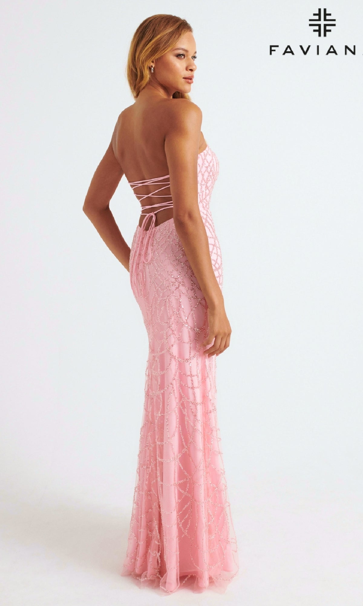 A woman models the Strapless Faviana Long Glitter-Print Prom Dress, featuring a fitted silhouette and lace-up back, against a white background. The Faviana logo is displayed in the top right corner.